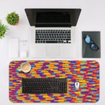 Infidu Artistic Desk Pad with a colorful mosaic pattern of red, yellow, blue, purple, and orange blocks arranged diagonally. Desk Mat with an Apple Laptop