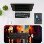 Desk pad featuring a vibrant nighttime city scene with bright colors reflecting off wet streets. Silhouette of a person with an umbrella in the center. Desk Mat with an Apple Laptop