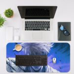 Desk pad featuring a manga-style anime character with white hair and a serious expression on a vibrant blue background. Desk Mat with an Apple Laptop