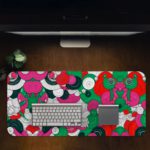 Colorful abstract desk pad with playful patterns, featuring pink, green, red, black, and white shapes resembling flowers and circles. Desk Pad in computer table