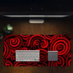 Desk pad with bold red and black spirals on a dark background, creating a hypnotic effect. Desk Pad in computer table