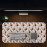 Desk pad with a white background featuring a pattern of small blue and purple flowers or geometric shapes. Design Kept on a computer table