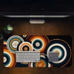 Infidu Artistic Desk Mat with concentric orange and white circular patterns on a dark blue or black background. Desk Pad in computer table