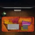 Infidu Artistic Desk Mat with abstract rectangular and trapezoidal shapes in warm tones of orange, red, purple, and yellow. Desk Pad in computer table