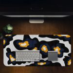 Infidu Artistic Patterns Desk Pad with a black background and large, irregular white and orange abstract shapes. Desk Pad in computer table