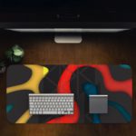 Infidu Artistic Desk Mat with bold curvy shapes in yellow, red, and blue on a dark black background. Desk Pad in computer table