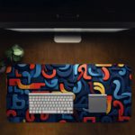 Infidu Desk Pad with a funky pattern of abstract curved shapes in blue, red, and yellow. Desk Pad in computer table