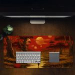 Desk pad featuring a colorful sunset over a forest, with warm shades of red, orange, and yellow. Trees in the foreground and a glowing sun in the sky. Desk Pad in computer table