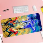 Infidu Artistic Desk Mat with dynamic swirling abstract pattern in yellow, red, and blue on a dark background. Desk Pad with Keyboard and Mouse