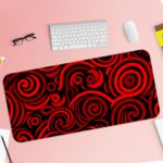 Desk pad with bold red and black spirals on a dark background, creating a hypnotic effect. Desk Pad with Keyboard and Mouse