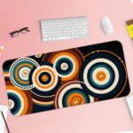 Infidu Artistic Desk Mat with concentric orange and white circular patterns on a dark blue or black background. Desk Pad with Keyboard and Mouse