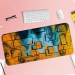 Infidu Artistic Desk Mat with an abstract geometric pattern in yellow, orange, and blue, covering the entire surface. Desk Pad with Keyboard and Mouse