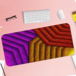 Infidu Artistic Patterns Desk Pad with a geometric zigzag pattern in warm hues of red, purple, and yellow, featuring a textured look. Desk Pad with Keyboard and Mouse