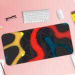 Infidu Artistic Desk Mat with bold curvy shapes in yellow, red, and blue on a dark black background. Desk Pad with Keyboard and Mouse