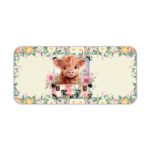 Desk pad with a playful cow design, yellow rose, and pink and white flowers in the background. Desk Pad kept on a plain white background