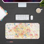 Infidu Artistic Desk Mat with speckled colorful dots in blue, red, yellow, and green on a white background. Design Kept on a computer table