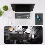 Desk pad with a grayscale illustration of a person in a fight, set against a gray and black background. Desk Mat with an Apple Laptop