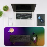 Gaming-themed desk pad with hands holding a game controller against a neon-like, futuristic background in deep purple, blue, and green colors. Desk Mat with an Apple Laptop