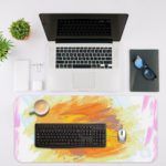 Infidu Artistic Desk Pad with colorful splashes of orange, pink, and purple on a white background. Desk Mat with an Apple Laptop