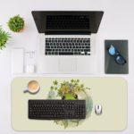 Desk pad with a playful frog design and a yellow flower on a white background. Desk Mat with an Apple Computer