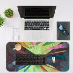 Infidu Artistic Desk Pad with angular abstract shapes in green, pink, purple, and yellow. Desk Mat with an Apple Laptop