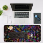 Infidu Artistic Desk Pad with elegant abstract shattered glass pattern in green, blue, purple, and yellow on a dark background. Desk Mat with an Apple Laptop