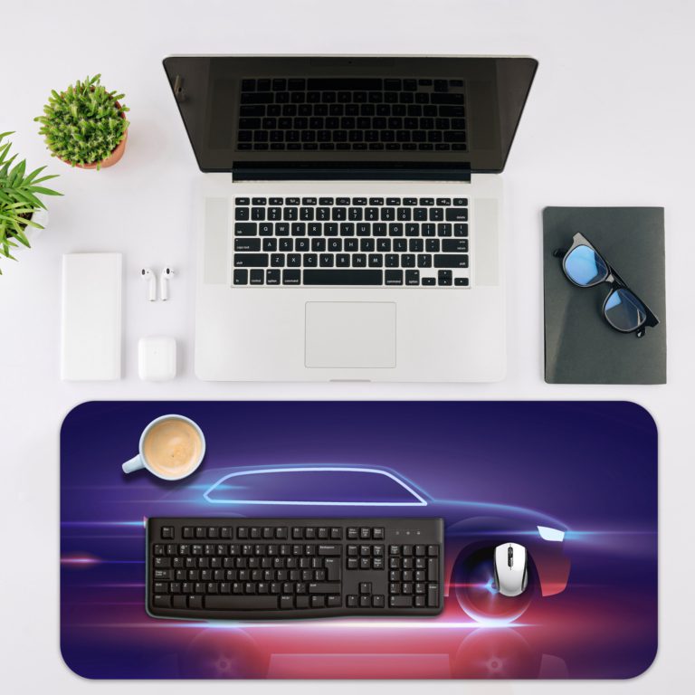 Desk mat showing a futuristic car silhouette with glowing blue, purple, and pink effects on a navy blue background. Desk Mat with an Apple Laptop