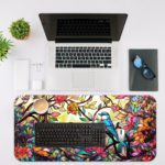 Illustration of two colorful parrots on a branch surrounded by pink, blue, and red flowers and leaves on the Infidu Artistic Animated Desk Mat with a laptop