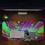 Gaming Desk Pad featuring a vibrant, randomly painted controller with a background in green, violet, and light yellow, designed for a unique and artistic look Desk Pad with Antique Video Game Design Kept on a computer table