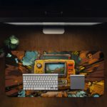 Infidu Tech Fusion With Joystick Desk Pad features a vibrant, colorful gaming controller and a natural background with trees, sea, and mountains Design of Antique Video Game in a desk pad on the table