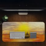 Desk mat featuring a sunset scene with a silhouette of a sailboat on an orange-gold sea, under a warm yellow and golden sky. Desk Pad in computer table