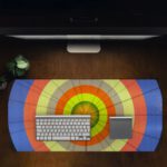 Infidu Artistic Desk Mat with circular pattern and concentric rings in orange, yellow, blue, and green. Desk Pad in computer table