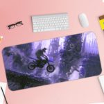 Desk pad with a silhouette of a motocross rider mid-jump against a foggy cityscape in blue and purple tones. Desk Pad with Keyboard and Mouse