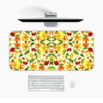 White desk mat with an autumn-themed floral pattern, featuring stylized leaves and flowers in orange, yellow, and green tones. Desk Mat with a computer