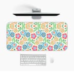 White desk mat with a colorful floral pattern featuring pink, orange, blue, and green flowers, designed for a unique workspace touch. Desk Mat with a computer