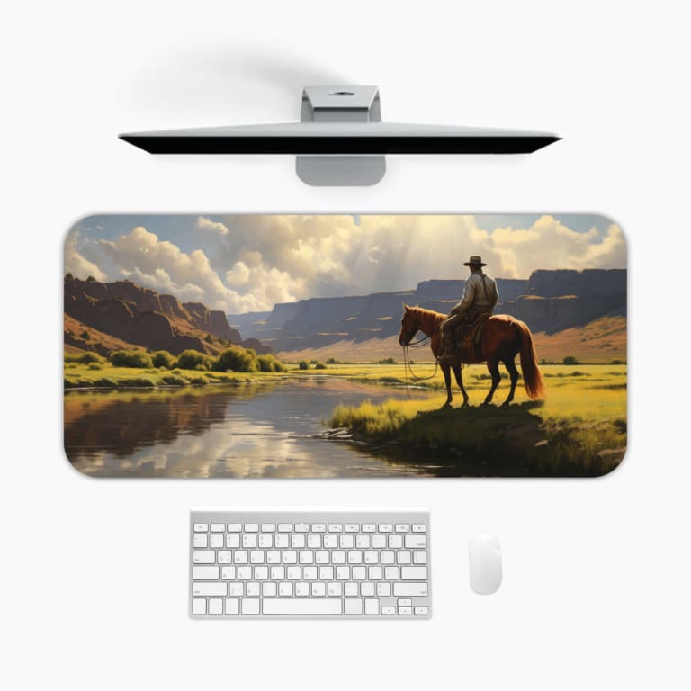 Infidu Horse Rider Desk Pad with a natural landscape showing a person on horseback against mountains, a river, and grassy fields. A desk pad under the computer