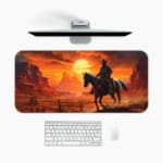 Desk pad featuring a horse rider against a vivid desert sunset with warm colors and rugged rock formations. A desk pad under the computer