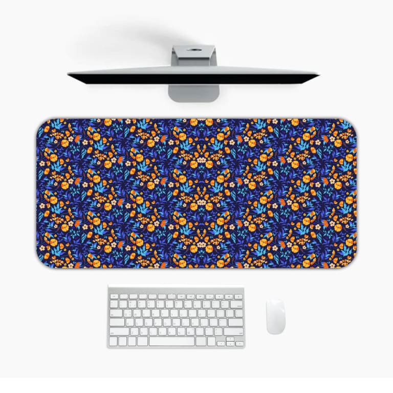 Dark blue desk mat with a dense pattern of small orange and yellow flowers and green leaves, adding vibrant charm to your workspace. Desk Mat with a computer