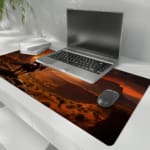 Horse rider in scenic desert sunset with large rock formations and warm sunset colors on a desk pad. the desk pad is kept on the laptop