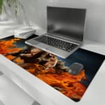 Dynamic desk pad featuring a fiery horse rider in action with vivid flames and a dark background. the desk pad is kept on the laptop