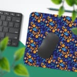 Dark blue desk mat with a dense pattern of small orange and yellow flowers and green leaves, adding vibrant charm to your workspace. Desk Pad with Keyboard and Mouse