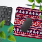 Infidu Desk Pad with a red background, featuring pink, white, and black Christmas trees, reindeer, and snowflakes in a knitted pattern. Desk Pad with Keyboard and Mouse