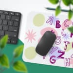 Infidu Alphabet Desk Pad with a white background featuring colorful letters and star shapes in various styles and colors. Desk Pad with Keyboard and Mouse