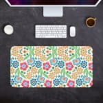 White desk mat with a colorful floral pattern featuring pink, orange, blue, and green flowers, designed for a unique workspace touch. Desk Pad kept on a gray background