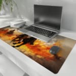 Desk pad with a rider on a brown horse amidst a fiery background with orange and yellow flames. the desk pad is kept on the laptop