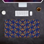 Dark blue desk mat with a dense pattern of small orange and yellow flowers and green leaves, adding vibrant charm to your workspace. Desk Pad on the computer table in gray background