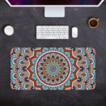 Infidu Desk Pad featuring intricate mandala design with blue background and vibrant orange, red, and white details. Desk Pad with Keyboard and Mouse in gay background