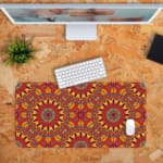 Infidu Desk Pad with bold mandala-like pattern and vibrant red, yellow, and orange details. Desk Pad kept on a orange background