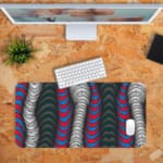 Infidu Vector Pattern Desk Pad featuring wavy lines in gray, red, and teal on a dark gray or black background. Desk Pad Design Kept on a computer table