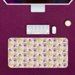 White desk mat with a medium-sized floral pattern in pink, yellow, and purple flowers, adding a vibrant and creative touch to your desk. Desk Pad kept on a pink background